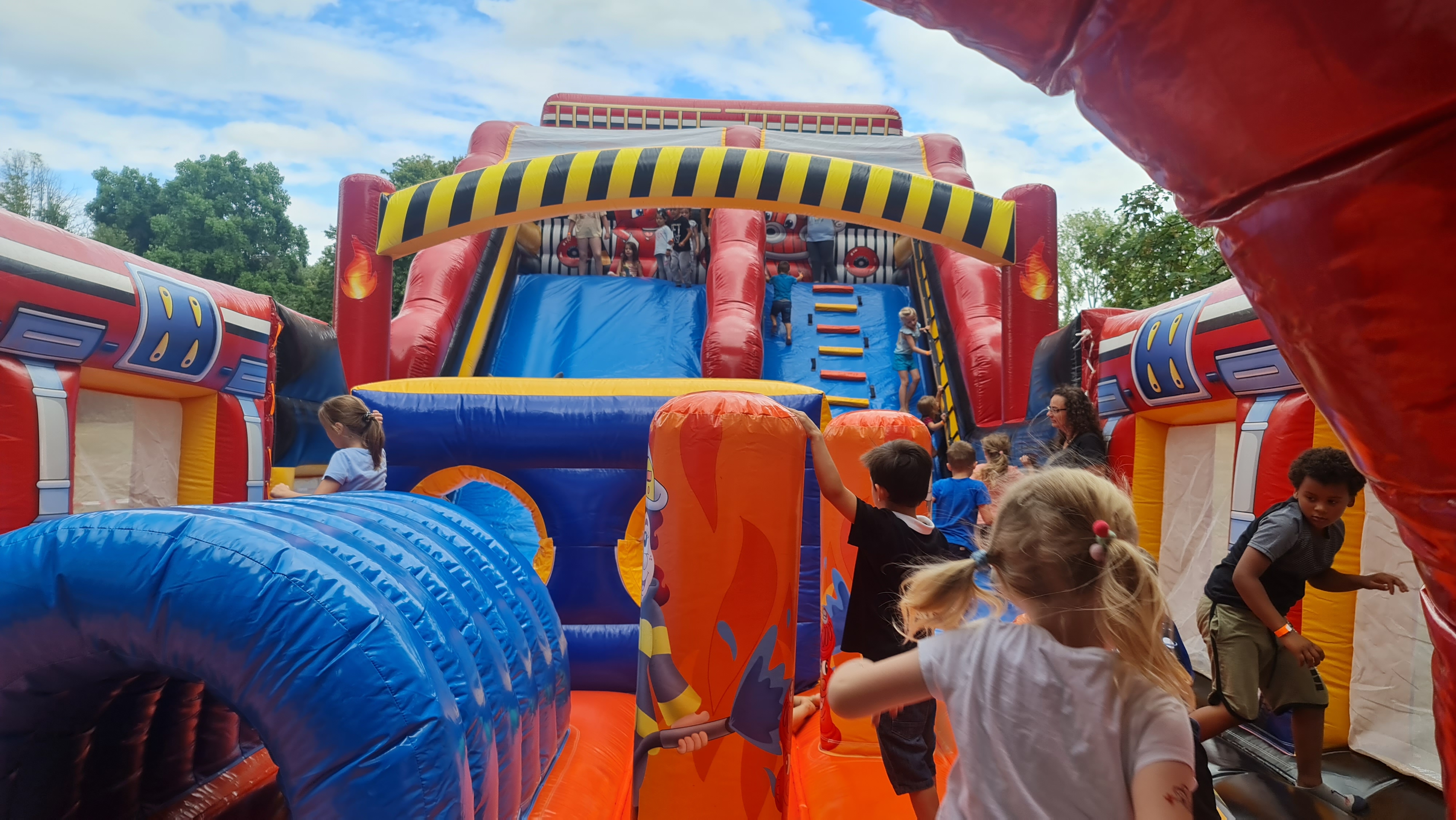 Kinder spielen fröhlich in einer bunten Hüpfburg mit Rutschrampen im Freien.