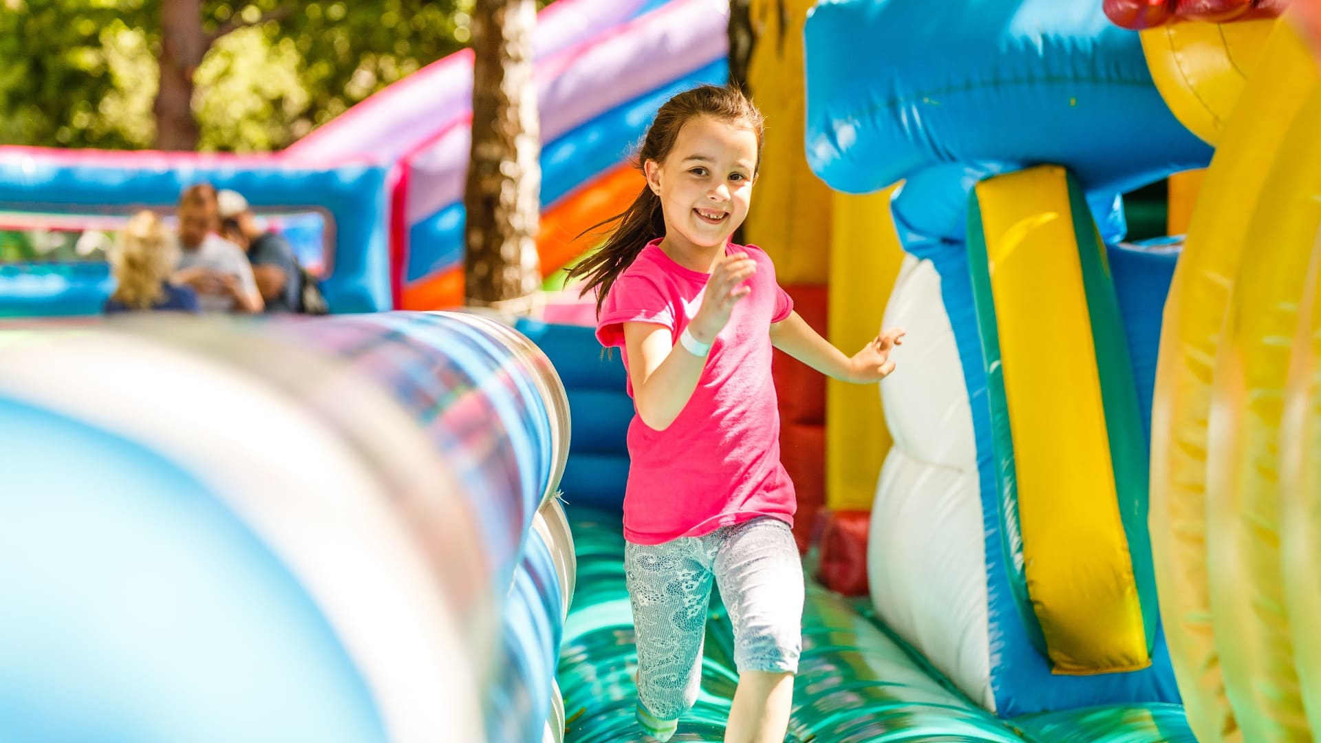 Happy little girl having lots of fun on a jumping castle during sliding.