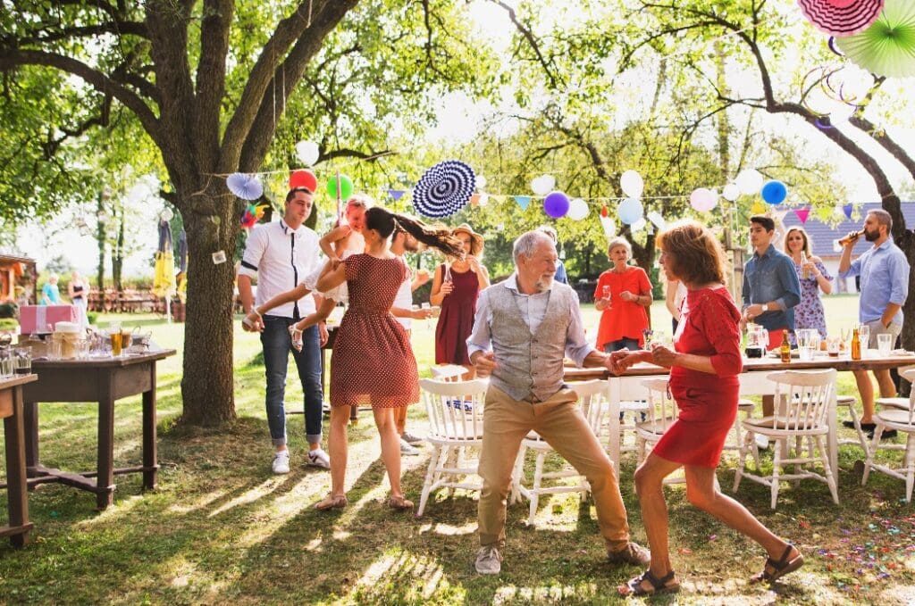 A senior couple and family dancing on a garden party outside in the backyard.