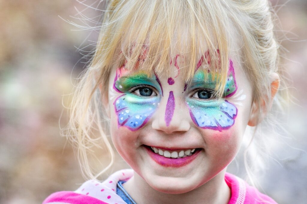 Glückliches geschminktes Kind als bunter Schmetterling