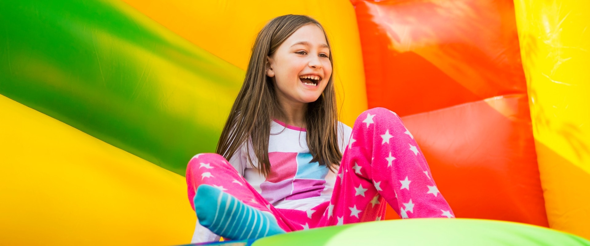 Happy little girl having lots of fun on a jumping castle during sliding.