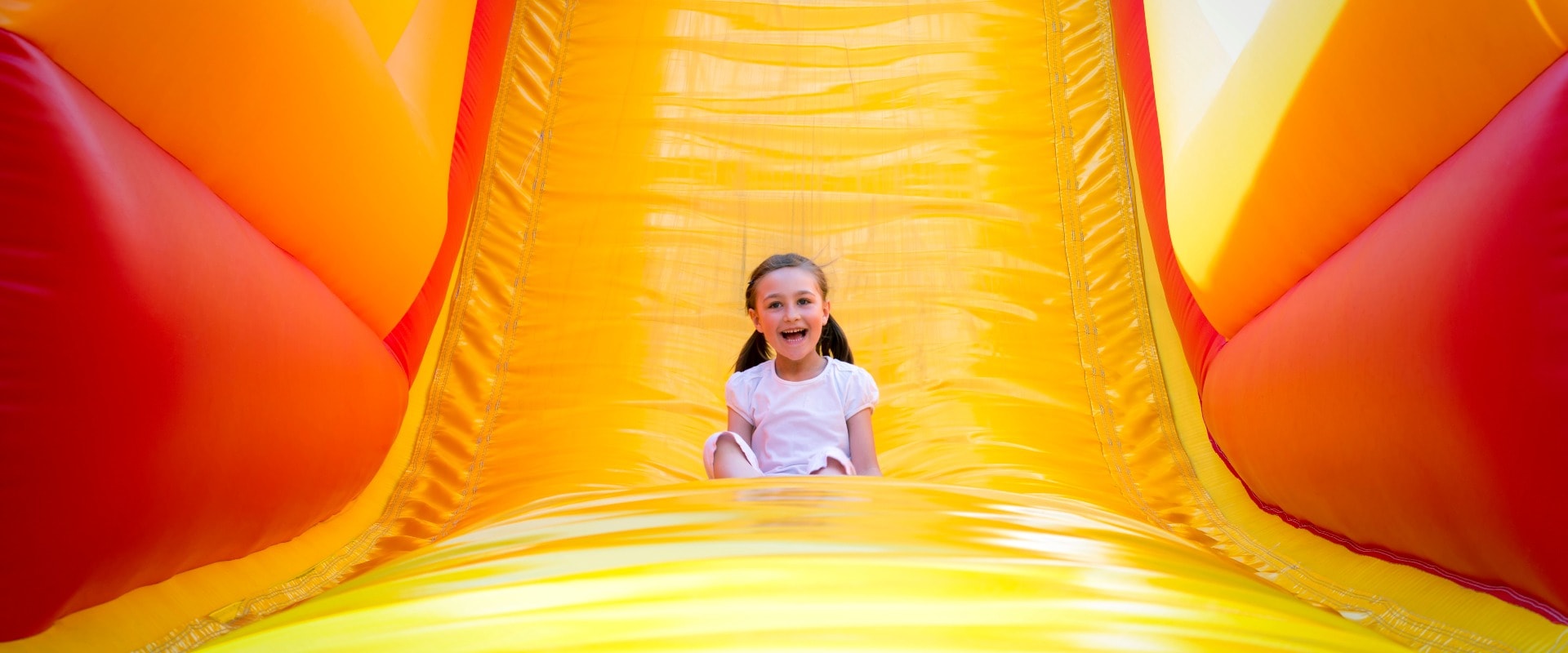 Happy little girl having lots of fun on a jumping castle while sliding.