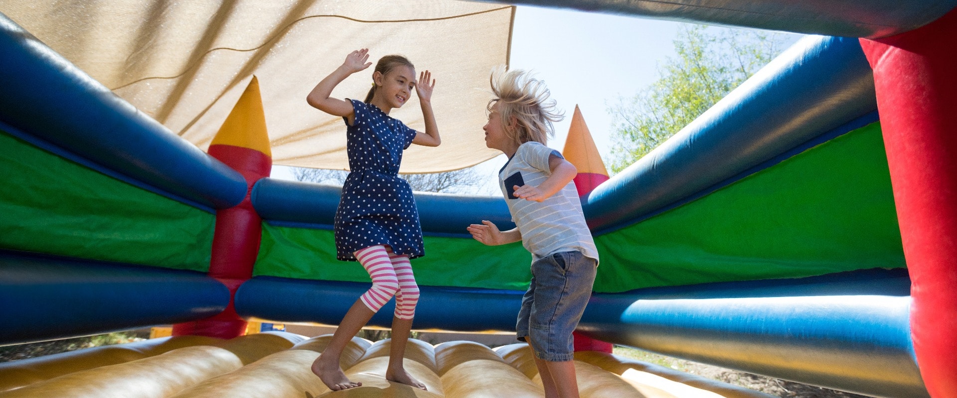 Happy siblings jumping on bouncy castle at playground