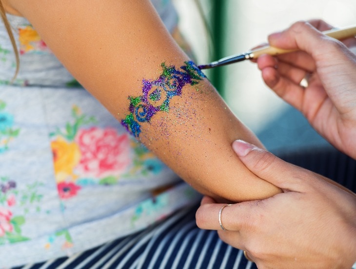 Little girl getting glitter tattoo at birthday party