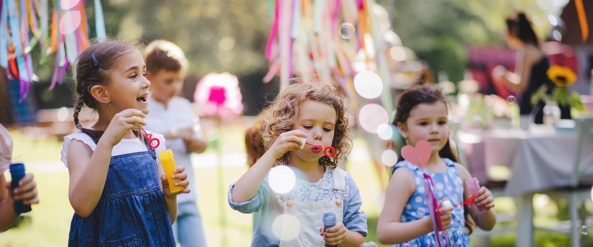 Small children outdoors in garden in summer, playing with bubbles.