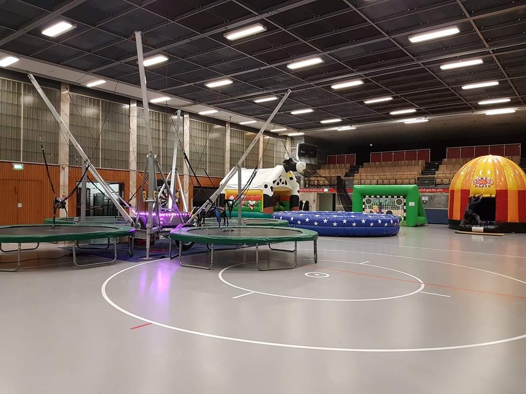 Eine leere Halle mit Trampolinen, Hüpfburgen und bunten Spielgeräten.