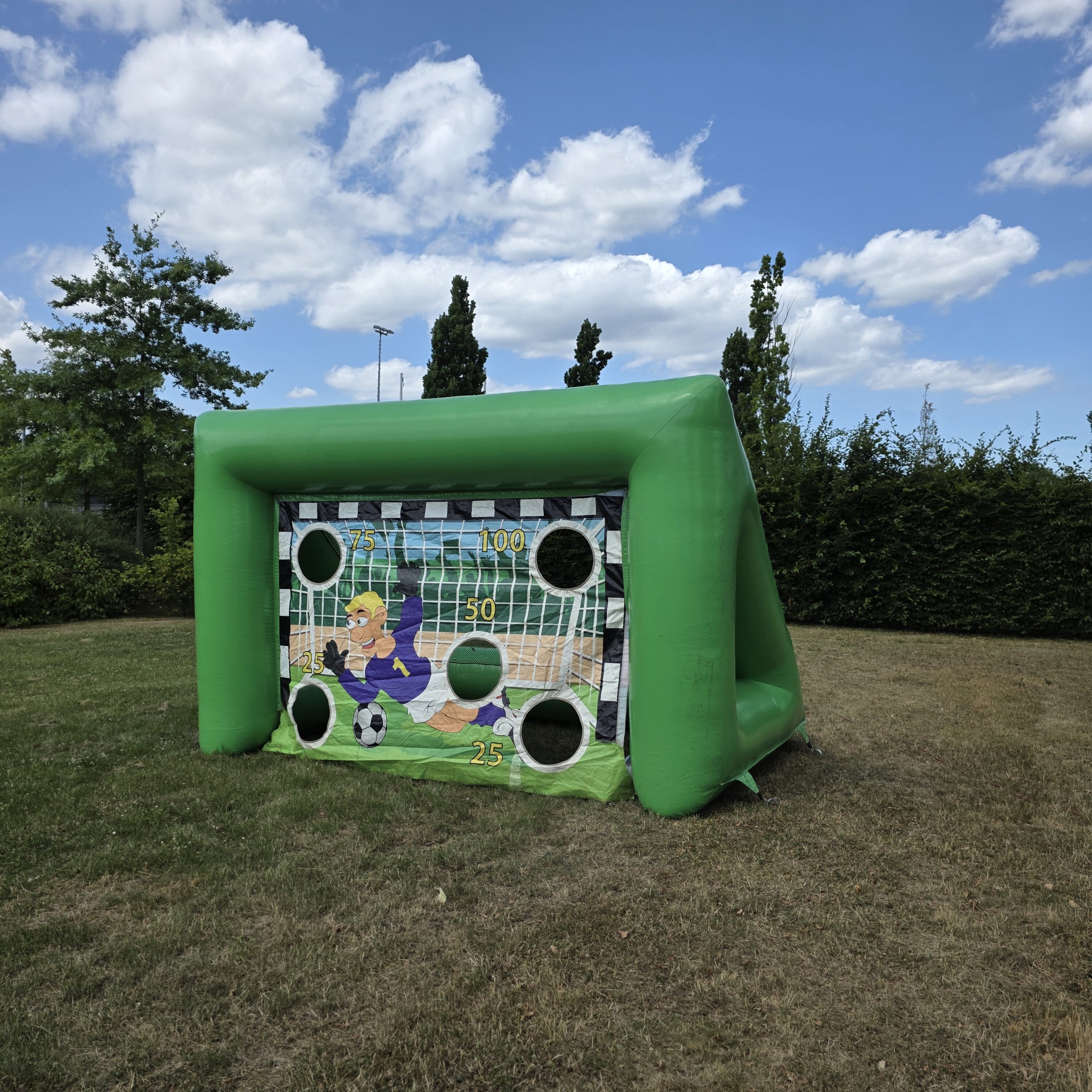 Aufblasbares Torzielspiel auf Rasen, grünes aufblasbares Gestell, bunte Torwand mit Löchern.